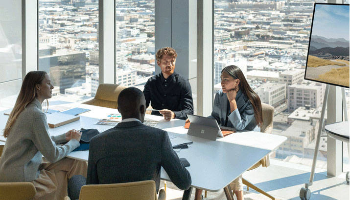 vier Personen Arbeiten in einem Meetingraum zusammen vor einem Surface Hub