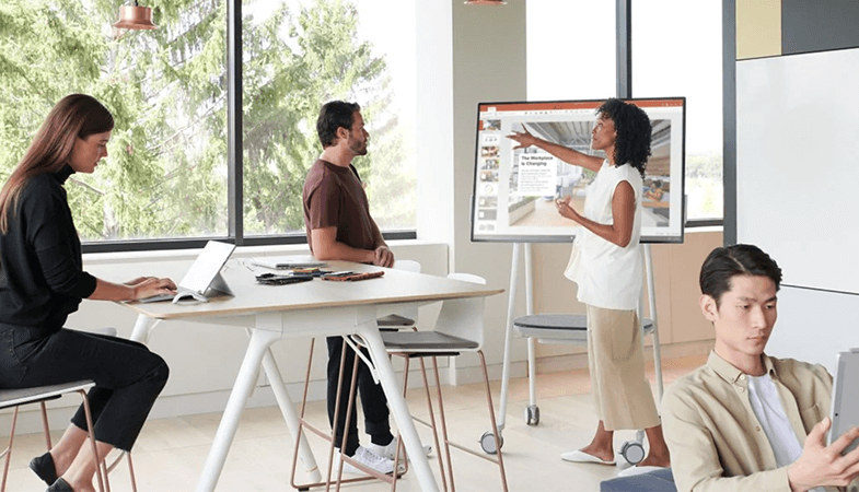 In einem Open Workspace präsentiert eine Frau eine PowerPoint Präsentation am Surface Hub