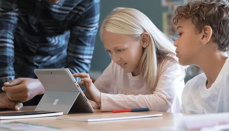 An einem Schreibtisch im Klassenraum tippt ein Mädchen auf den Touchscreen des Surface Go 