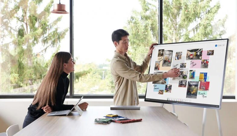 Ein Mann präsentiert einer Frau etwas auf dem Surface Hub 2