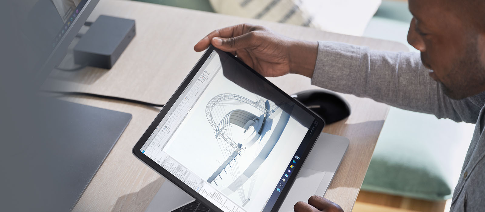 Eine Person sitzt an einem Schreibtisch und arbeitet mit dem Surface Laptop Studio 