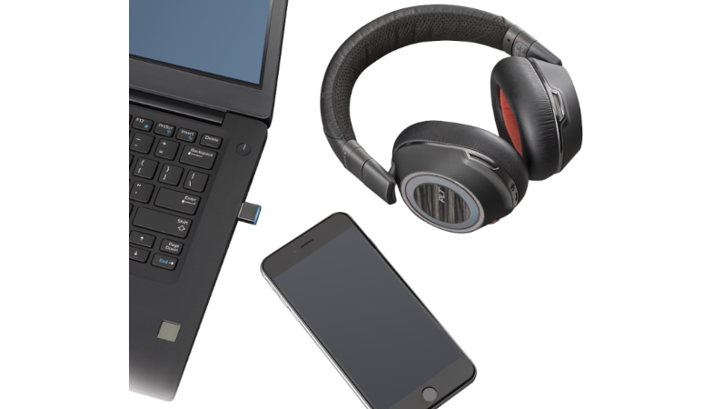Das Voyager Focus 8200 UC Headset ist neben einem Laptop und einem Smartphone platziert 