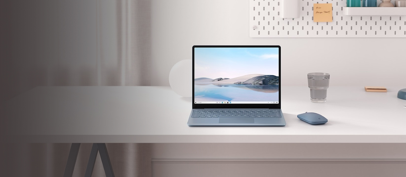 Der Surface Laptop Go 2 in Eisblau steht auf einem Schreibtisch 