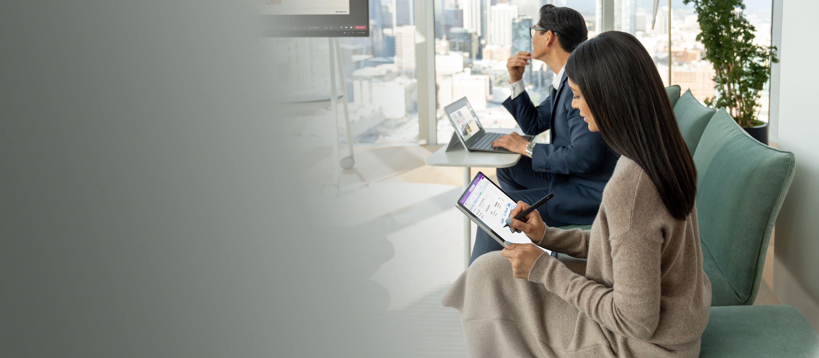 Ein Surface Pro 9 in Platin steht auf einem Tisch vor einem Mann während eines Meetings