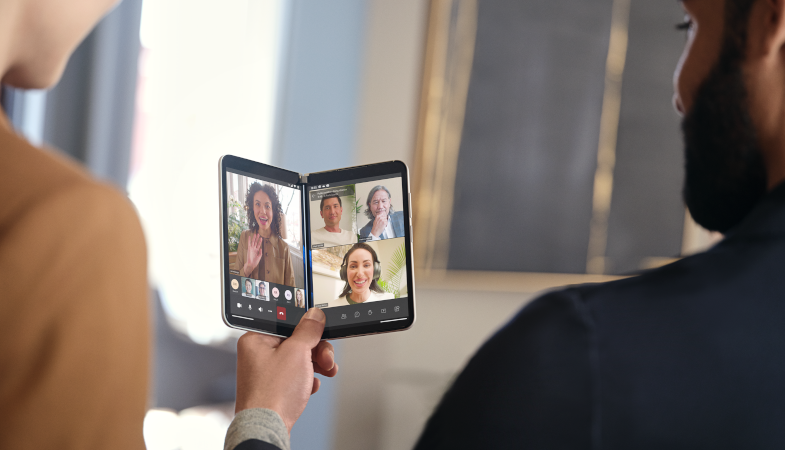 A person is holding a Surface Duo 2 with a Microsoft Teams meeting running on both screens