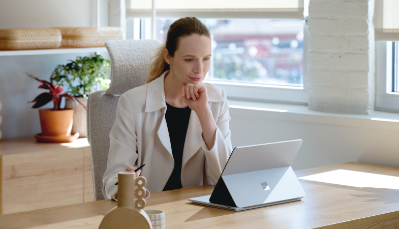 Eine Person sitzt an einem Schreibtisch und arbeitet mit dem Surface Laptop Studio im Bühnenmodus