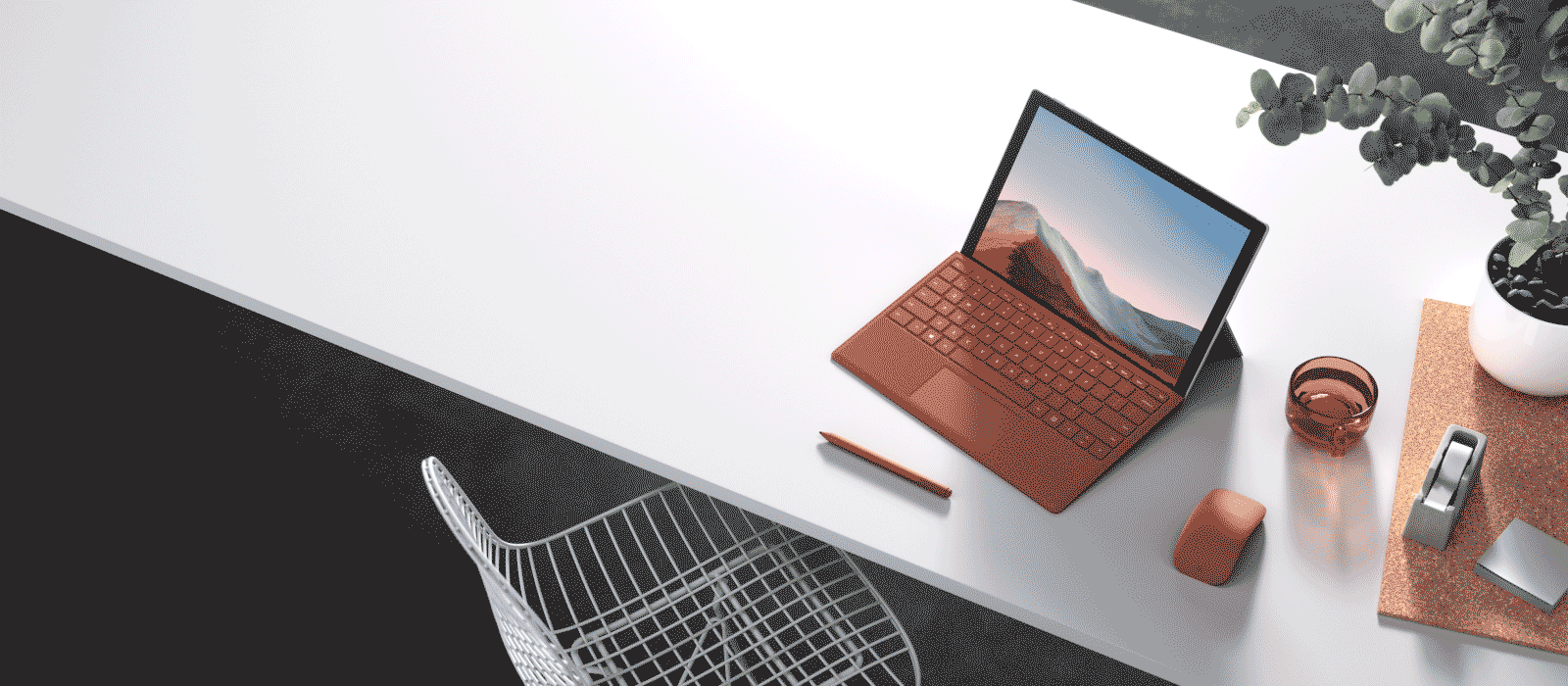 En Surface Pro 7 plus med en valmuerød Type Cover står på et skrivebord med andet Surface-tilbehør 