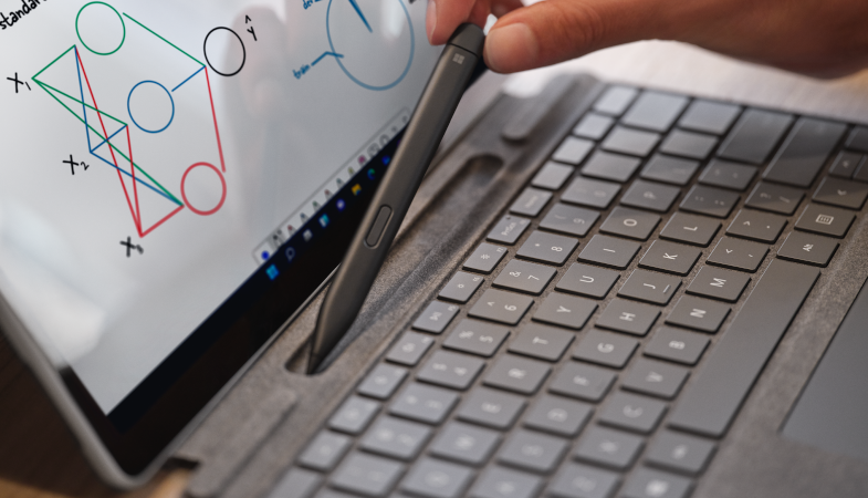 Detailaufnahme des Surface Pro Signature Keyboard, wie eine Person den Surface Slim Pen aus der Aufbewahrungsmöglichkeit nimmt