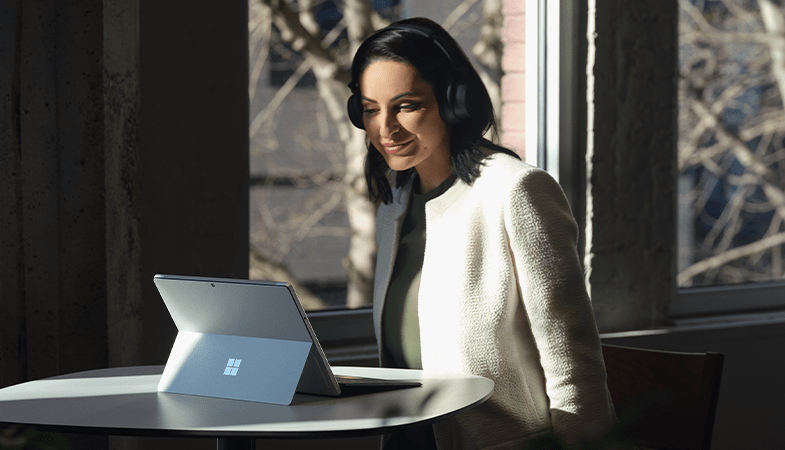 Eine Person sitzt vor einem Surface Pro 8 in Platin mit aufgeklapptem Kickstand und Surface Pro Signature Keyboard