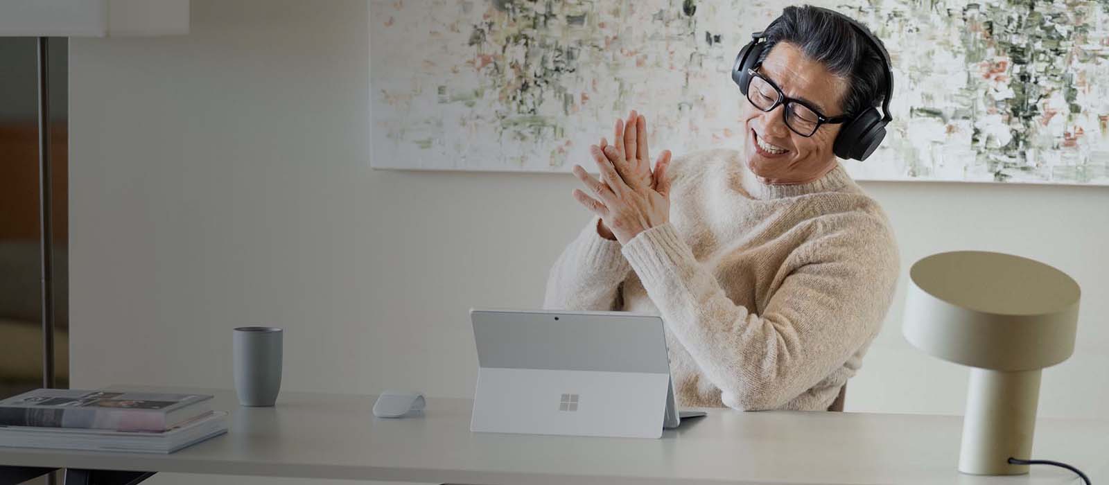 Ein Surface Pro 9 in Platin steht auf einem Tisch vor einem Mann während eines Meetings