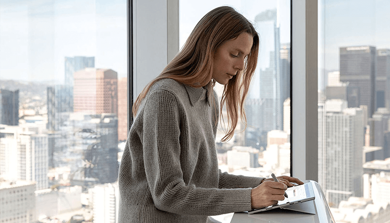 Eine Frau sitzt am Schreibtisch und arbeitet am Surface Pro