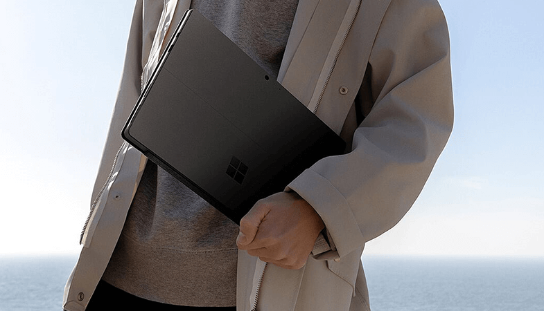 Ein Mann steht am Meer und hält das Surface Pro im Arm