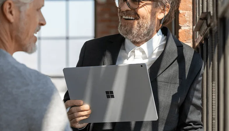 Zwei Männer stehen sich gegenüber, einer von ihnen hält ein Surface Book in der Hand 