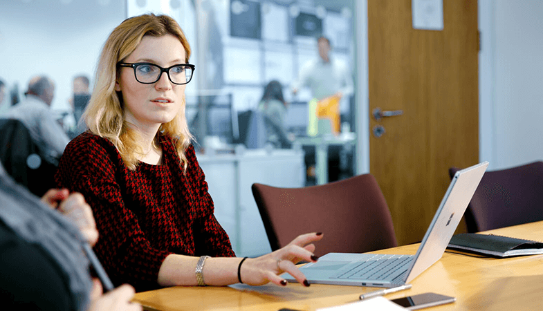 En kvinde sidder ved et skrivebord med en Surface Book