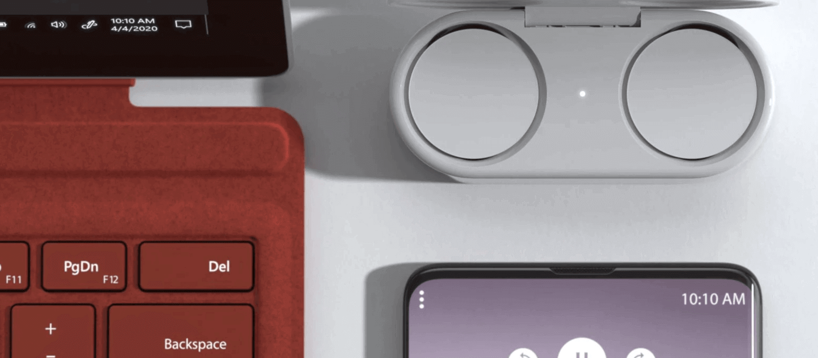 The charging case with the included Surface Earbuds is placed next to the Surface Pro 7 with the poppy-red Type Cover and a Smartphone