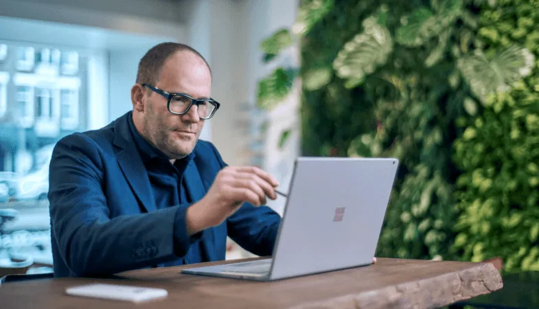 Ein Mann arbeitet an einem Tisch auf dem Display des Surface Books mit dem Surface Pen 