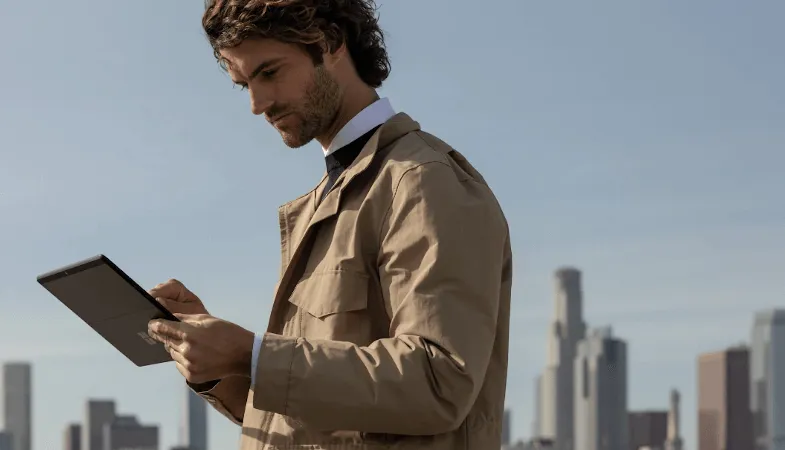 Die erstklassigen Cloudlösungen in Microsoft 365 ermöglichen einen effizienteren Arbeitsalltag Ein Mann steht und hält ein Surface Pro in der Hand