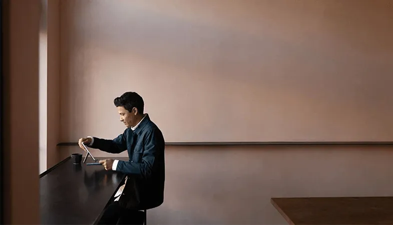 Ein Mann sitzt in einem leeren Raum und arbeitet an einem Surface Go