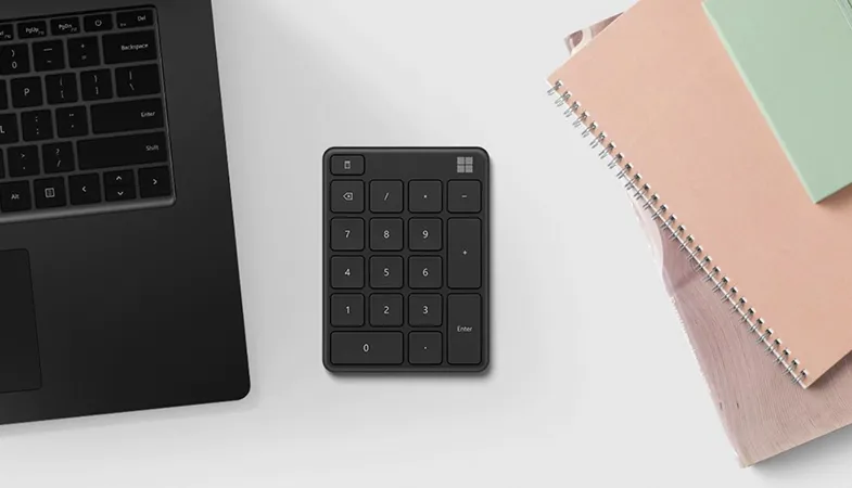 Das Microsoft Number Pad optimiert die Arbeit mit Zahlen Das Microsoft Number Pad in mattschwarz liegt neben einem Surface Laptop  auf einem Arbeitsplatz