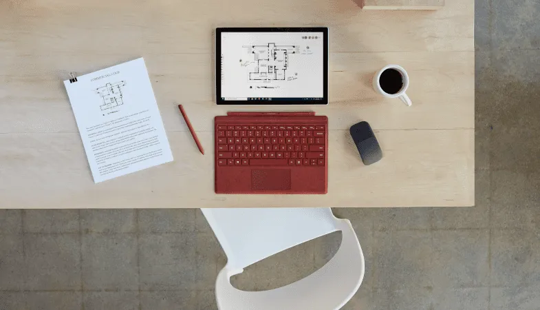 Bird's eye view of a desk on which the Surface Pro is placed next to a Type Cover, Surface Pen and Surface Arc Mouse. 