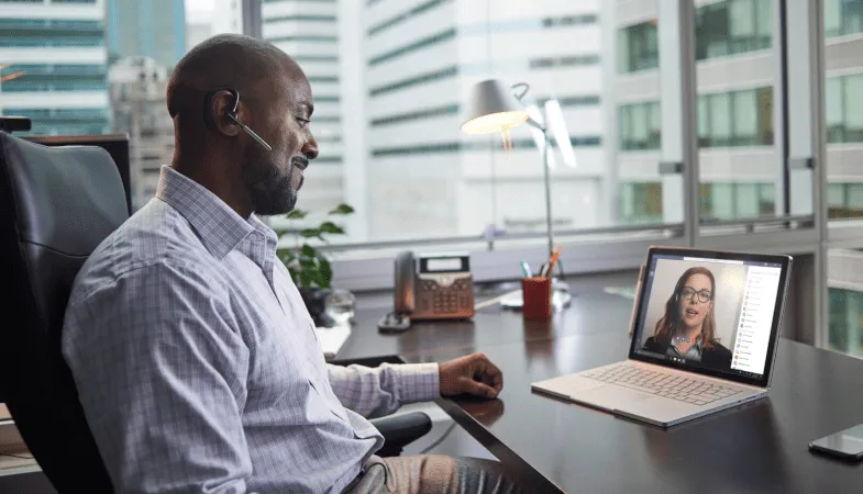 Surface Business Support Service  At a desk, a man talks to a woman on the phone via Microsoft Teams
