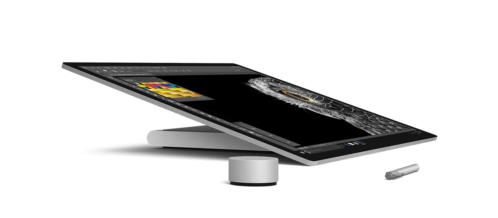 The Surface Studio 2 is tilted in studio mode, a Surface Pen and a Surface Dial are next to it