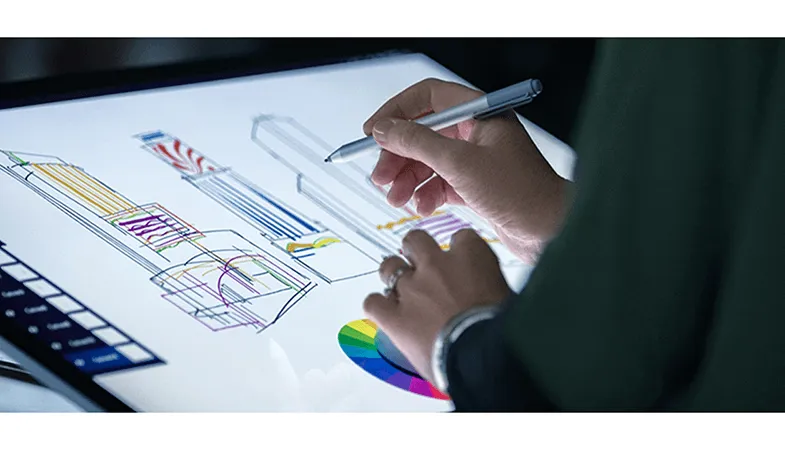 Das Surface Dial liegt auf dem Surface Studio 2 und dient einer Person beim Zeichnen mit dem Surface Pen zur Farbauswahl