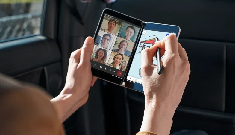 Eine Person hält das Surface Duo 2 im Compose Mode in der Hand und fertigt während eines MS Teams Meetings Notizen an