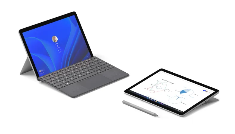 Ein Surface Go 3 mit Type Cover in Platin im Laptop-Modus ist neben einem Surface Go 3 im Studio-Modus, vor dem ein Surface Pen in Platin liegt, platziert