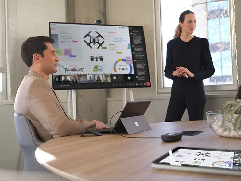 Ein Mann und eine Frau sind in einem Meeting mit dem Surface Hub 3