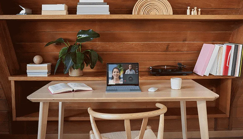 An ice blue Surface Laptop Go 2 stands on a desk in front of a shelf