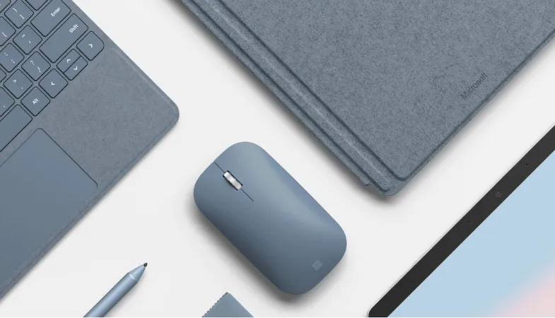 Die Surface Mobile Mouse in Eisblau ist zwischen zwei Surface Go Type Cover und dem Surface Pen in Eisblau sowie einem Surface Go platziert 