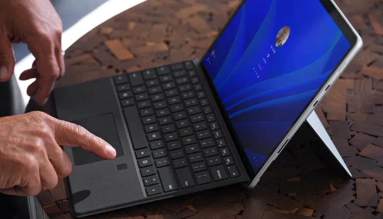 Surface Pro Signature Keyboard mit Fingerabdruckleser mit Alcantara-Veredelung Eine Detailaufnahme zeigt, wie eine Person den Fingerprintreader am Keyboard bedient