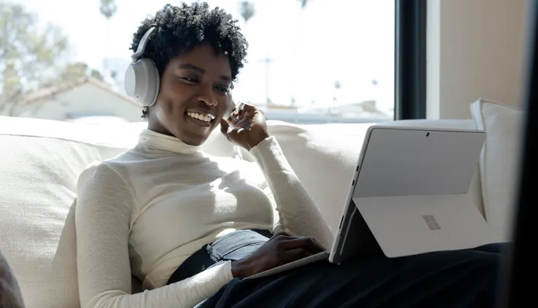 A person works on a Surface Pro 8 with Surface Pro Signature Keyboard and wears Surface Headphones on their head