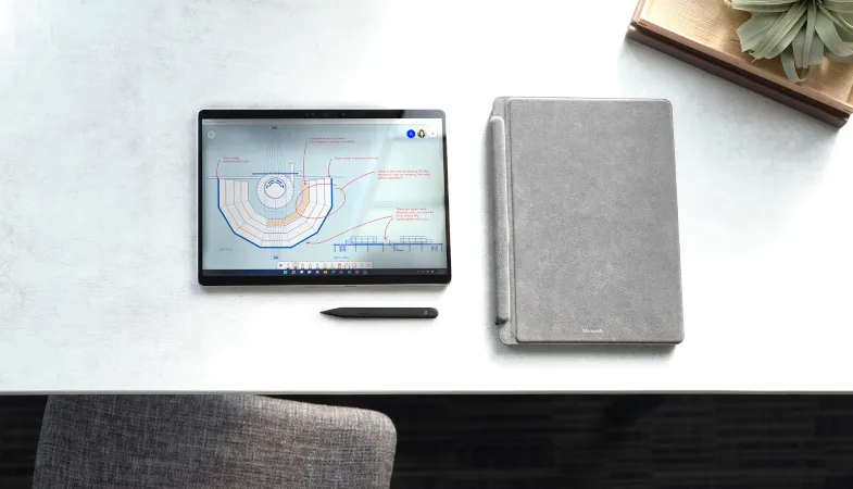 Ein Surface Pro 8 liegt im Tablet-Modus auf einem Schreibtisch, daneben liegt ein Surface Pro Signature Keyboard in Platin, darunter ein Surface Slim Pen 2 