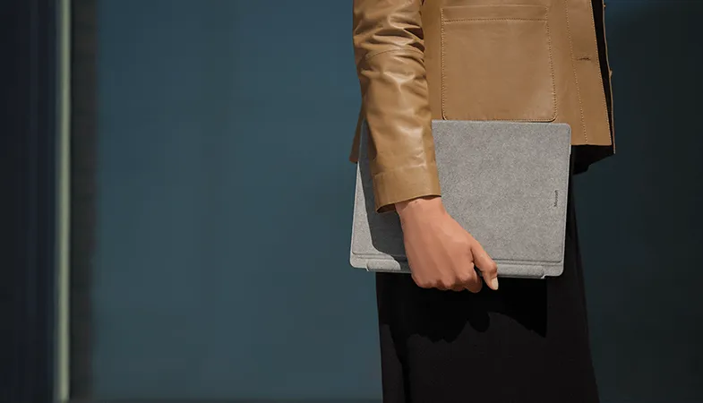 A person carrying the Surface Pro 8 with Surface Pro Signature Keyboard in grey under his arm
