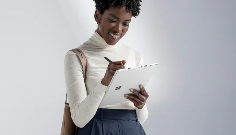 Eine Person hält ein Surface Pro in der Hand und schreibt etwas mit dem Surface Slim Pen 2 auf das Display 