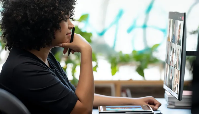 Eine Person arbeitet an einem Schreibtisch mit dem Surface Laptop Studio, dem Surface Slim Pen 2 und einem Monitor