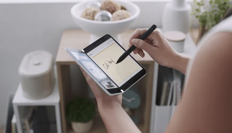 A woman uses the Surface Slim Pen to tap on a screen of the Surface Duo 