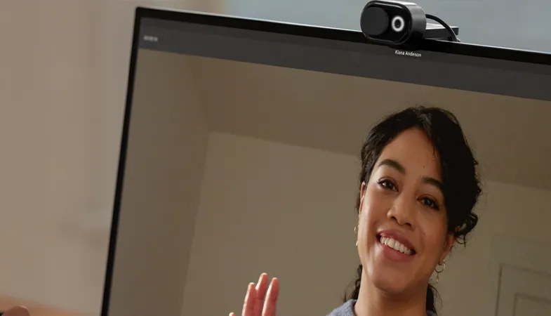 Automatic light adjustment and face retouching ensure a professional appearance  A person holds a video conference with the Microsoft Modern Webcam