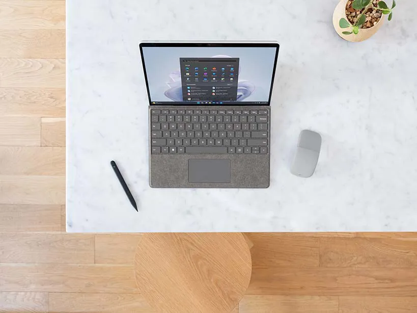 Ein Surface Pro 9 steht auf einem Tisch mit Surface Signature Keyboard und Surface Slim Pen 2