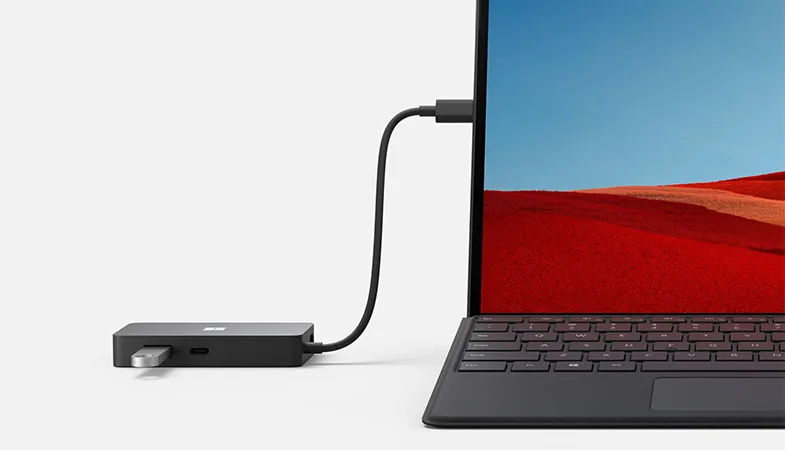The Microsoft Surface USB-C® Travel Hub is connected to a Surface Pro and has an USB-C stick attached to it