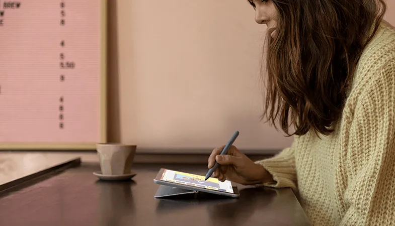 Eine Frau nutzt das Surface Go und schreibt darauf mit dem Surface Pen
