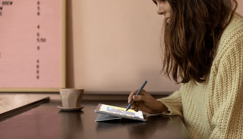 Microsoft Surface USB-C® Travel Hub flexible everyday work A woman is using the Surface Go and writing on it with a Surface Pen