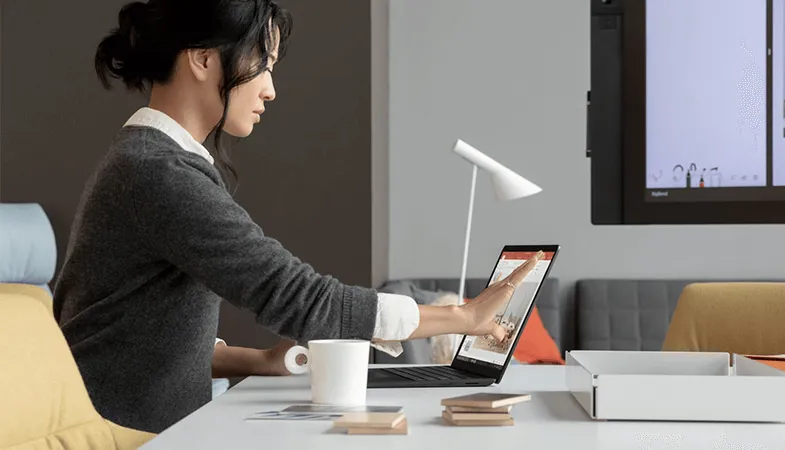 Real-time teamwork in all major office applications with Microsoft 365  A woman sitting at a table working with a Surface Laptop