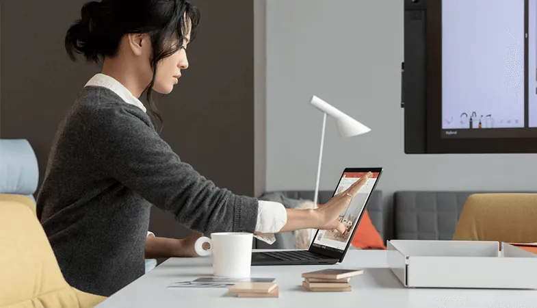 Eine Frau sitzt an einem Tisch und arbeitet mit dem Surface Laptop