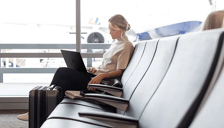Eine Frau sitzt am Flughafen und arbeitet am Surface Laptop