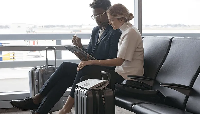  Two people sitting at the airport working on a Surface Pro