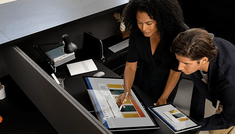Zwei Personen arbeiten gemeinsam am Surface Studio und Surface Pro