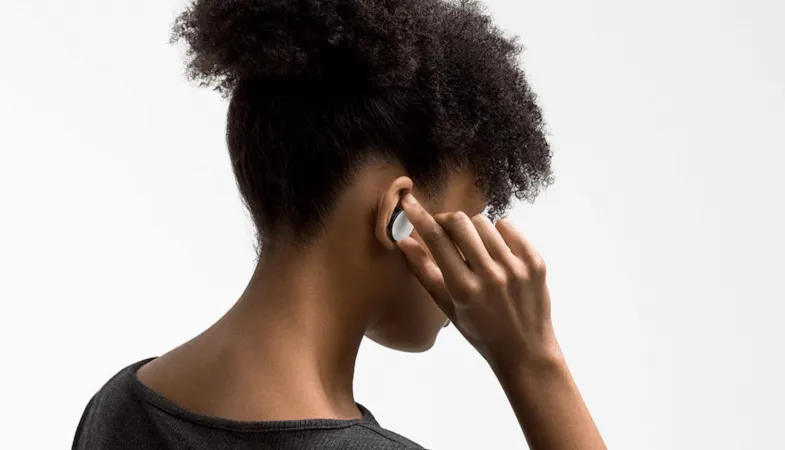 A woman wears the Surface Earbuds in her ears and works with them intuitively